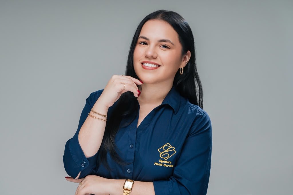 Eyni Mancia con camisa azul y logo de Eynita’s Multi-Service